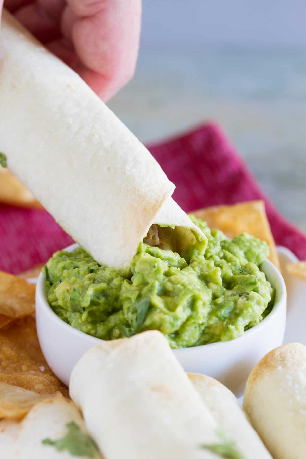 Dipping a Mexican Shredded Beef Baked Taquito into guacamole.