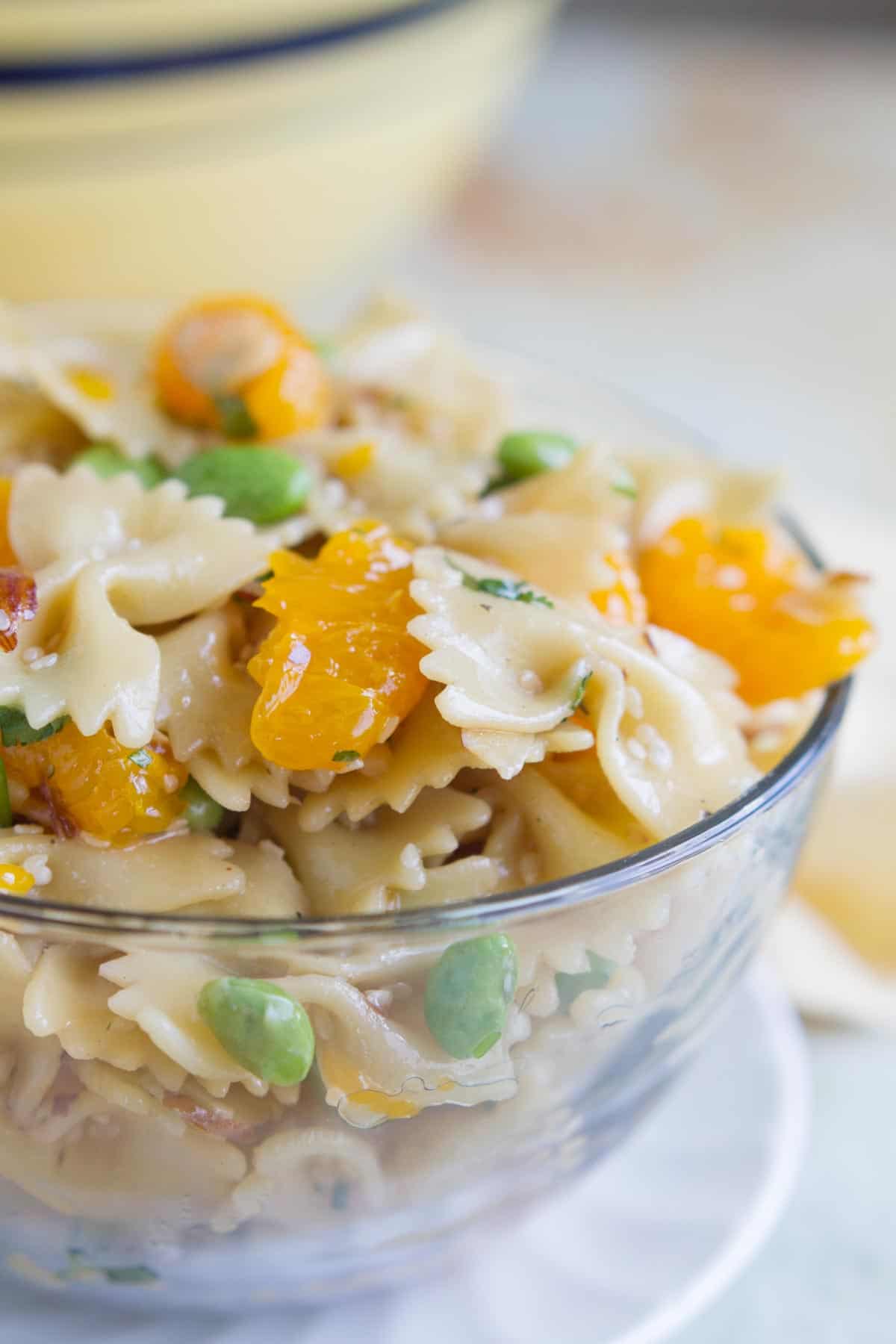 Oriental Pasta Salad with pasta, mandarin oranges, and edamame in a large glass bowl.