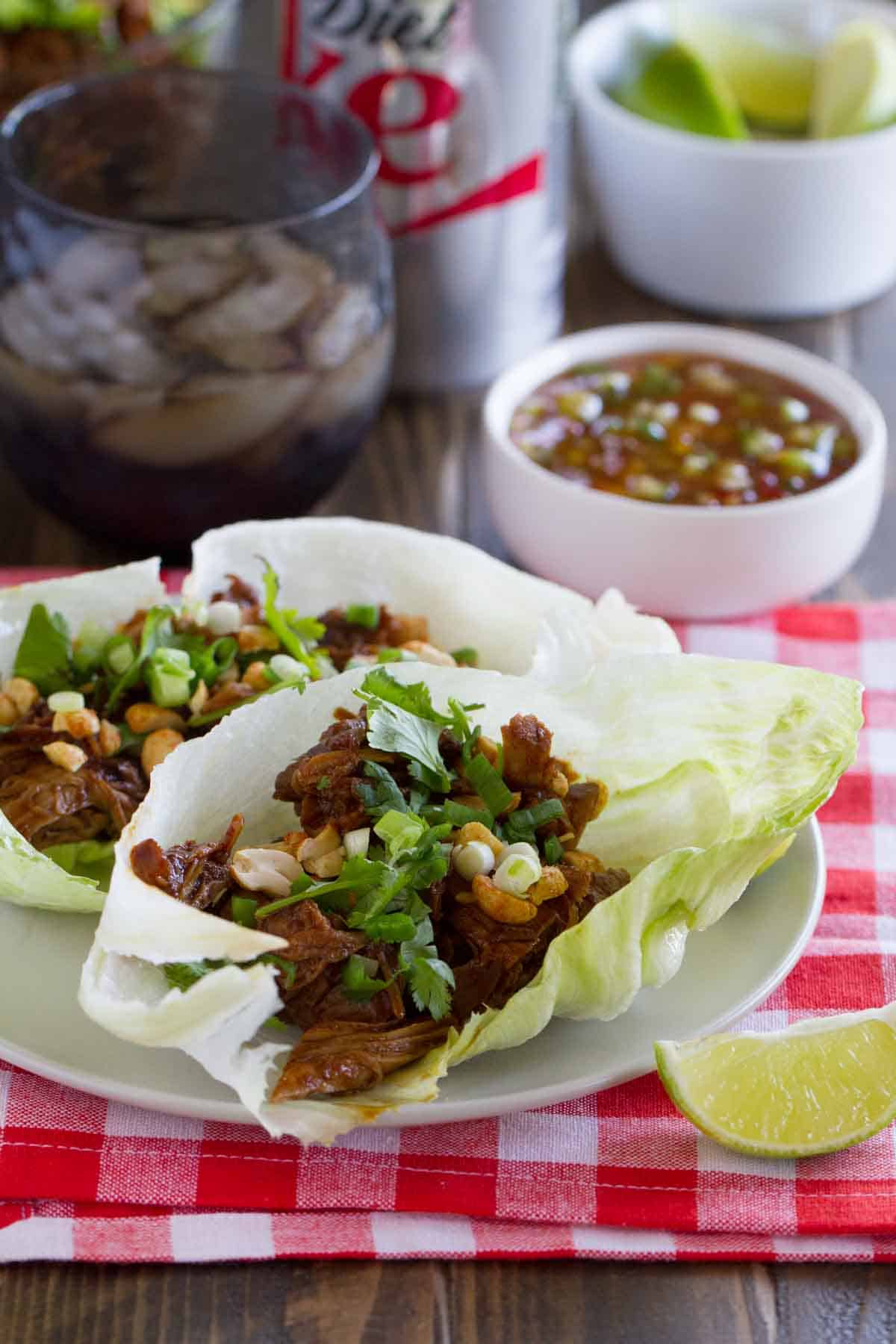 2 BBQ Pork Lettuce Wraps on a plate on top of a checkered cloth.