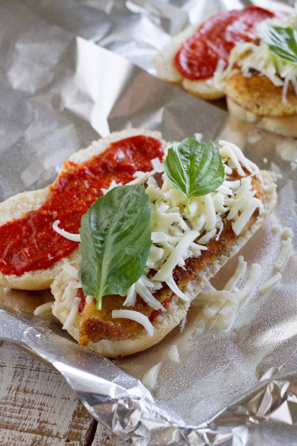 Baked Chicken Parmesan Sandwiches with roll, marinara, chicken parmesan, cheese, and basil in a foil packet.