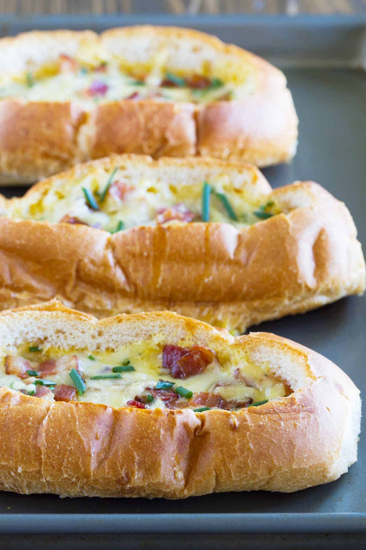 Three Baked Egg, Bacon, and Cheese Boats on a baking tray.