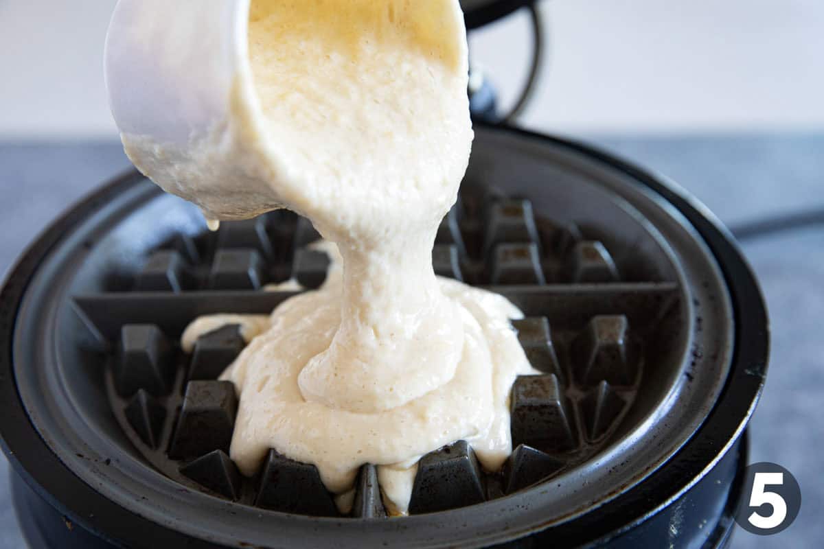 Pouring batter onto a waffle iron.