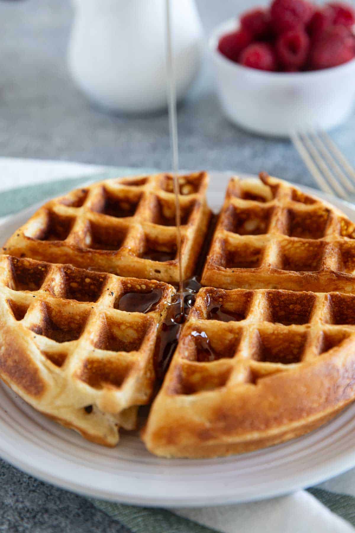 Pouring syrup onto a Belgian waffle.