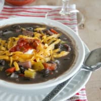 Bowl of black bean and ham soup, topped with cheese.