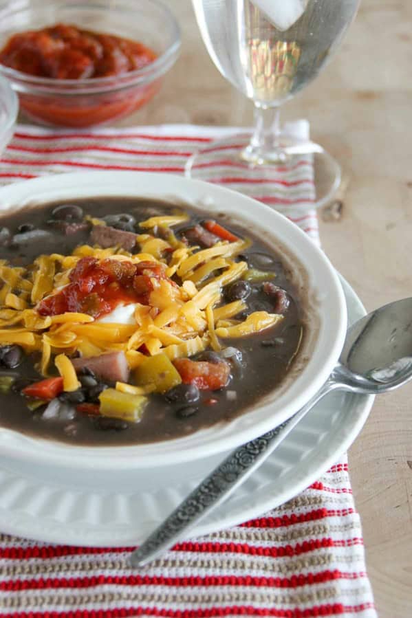 Bowl of black bean and ham soup, topped with cheese.