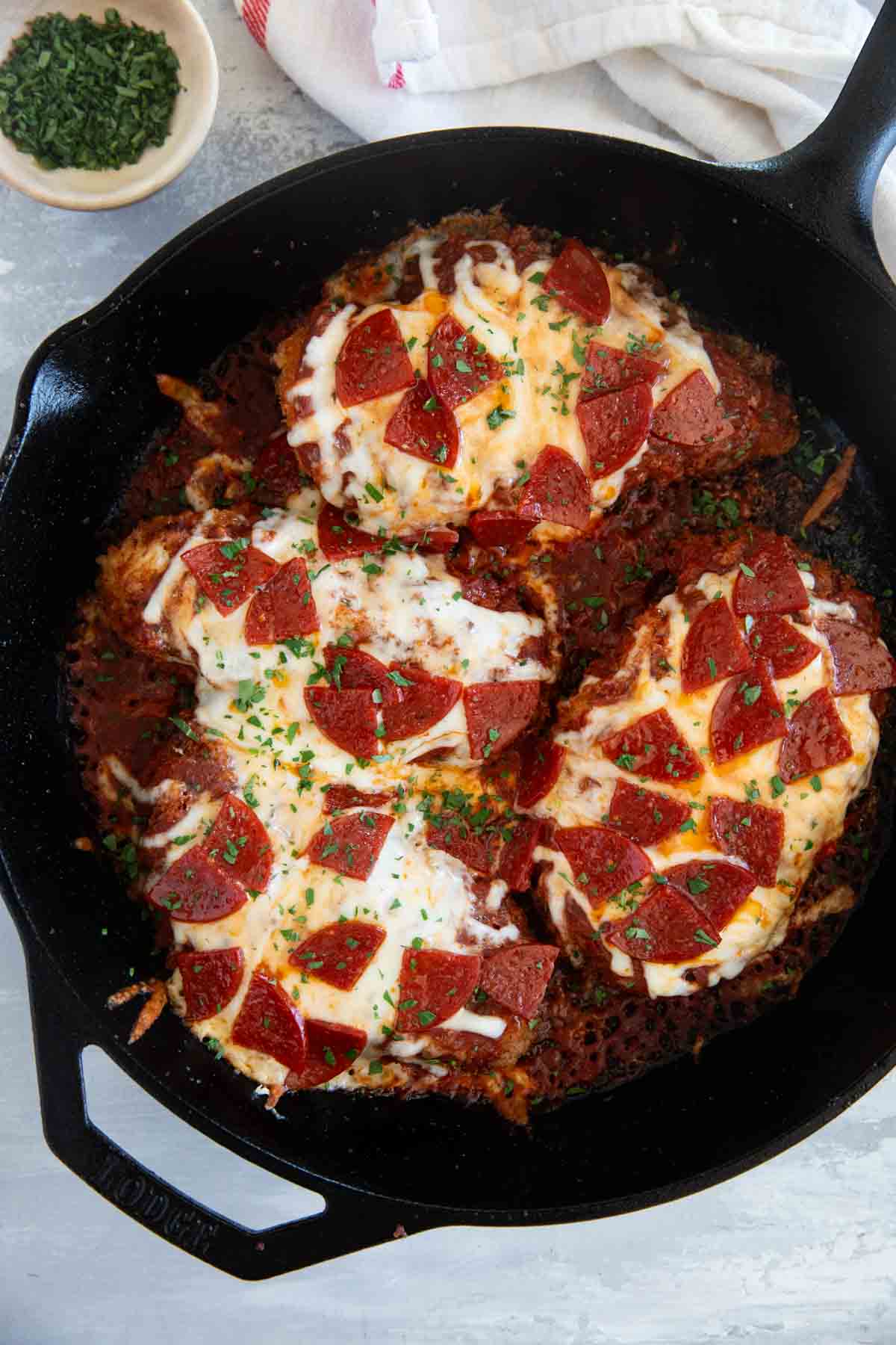 Chicken Pepperoni topped with cheese and tomato sauce in a cast iron skillet.