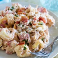 Serving of Creamy Tomato Tortellini with Chicken and Bacon on a plate with a fork.