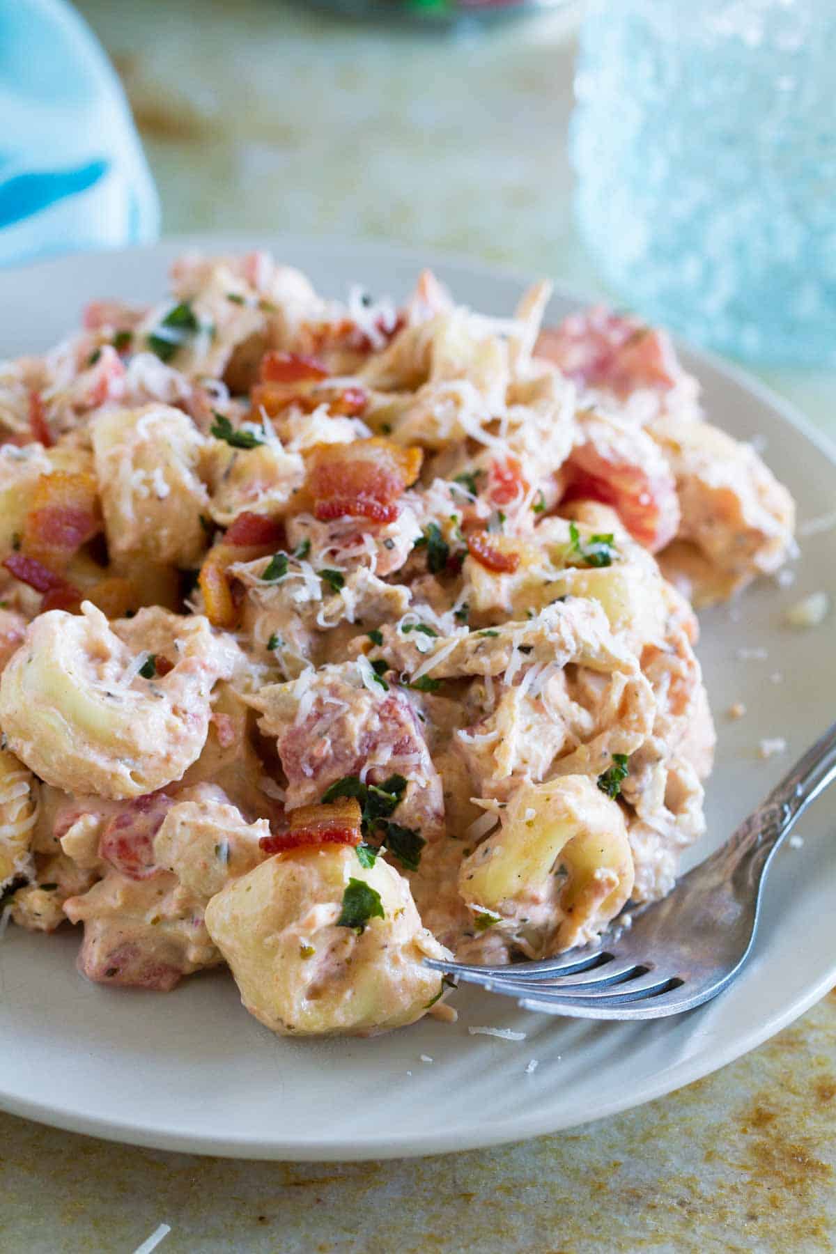 Serving of Creamy Tomato Tortellini with Chicken and Bacon on a plate with a fork.