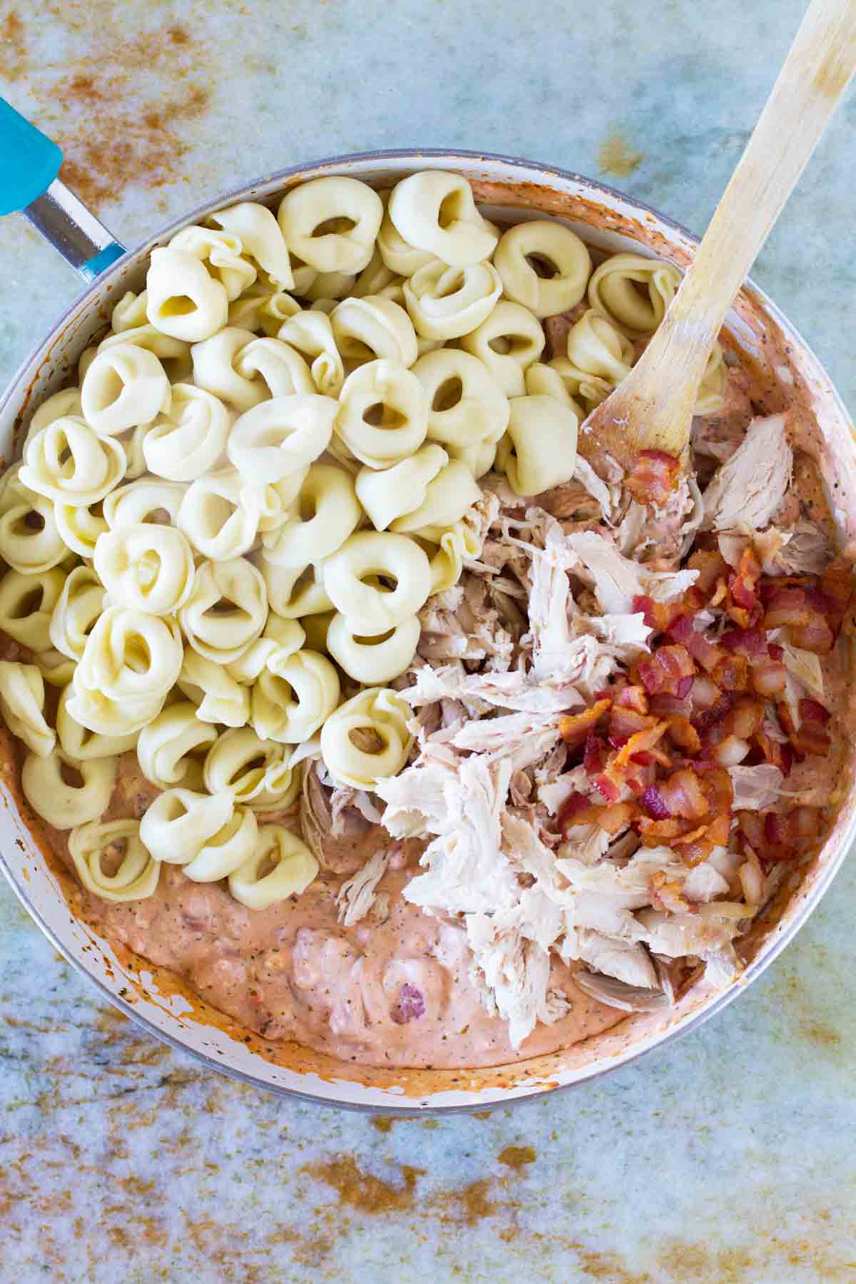 Combining ingredients to make Creamy Tomato Tortellini with Chicken and Bacon.