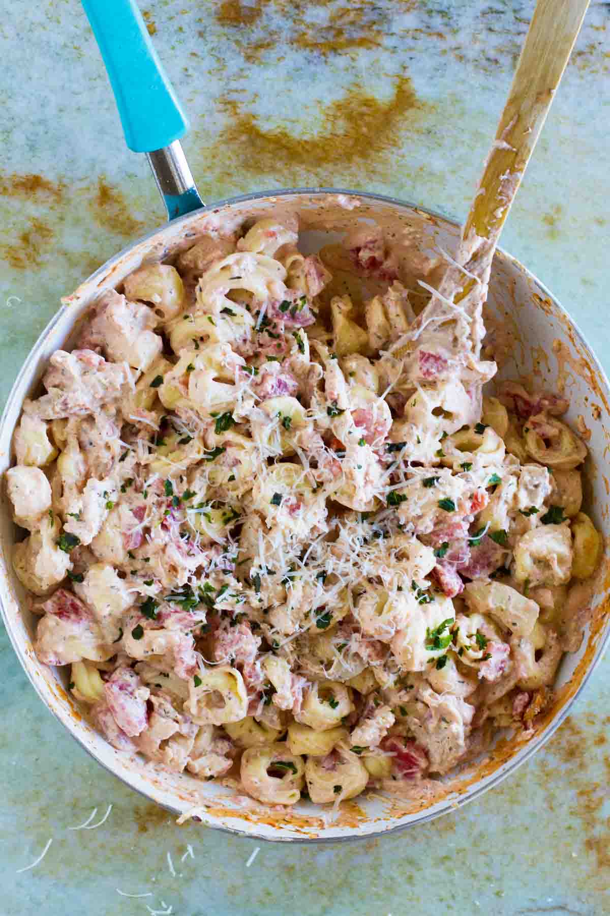 Skillet filled with Creamy Tomato Tortellini with Chicken and Bacon with parmesan cheese sprinkled on top.