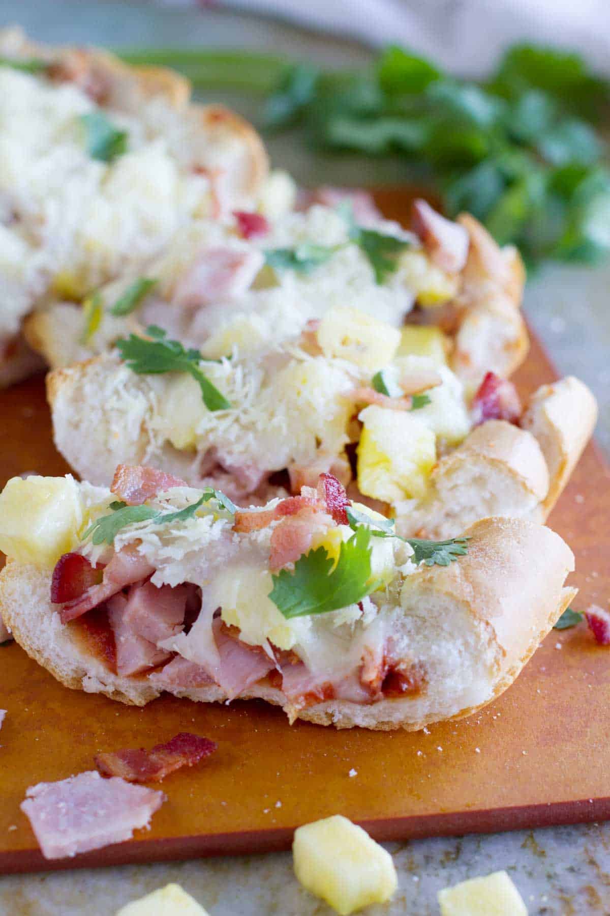 French Bread Hawaiian Pizza, topped with bacon, cheese, and cilantro.