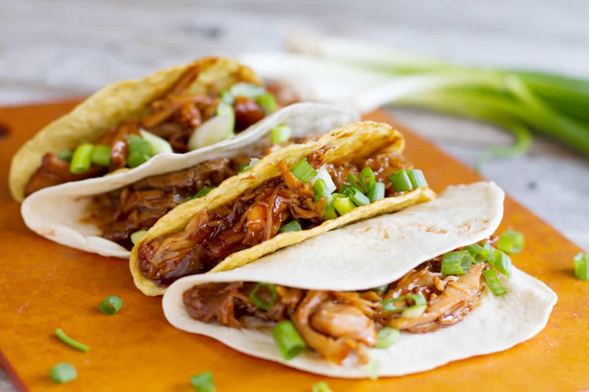 Honey Garlic Chicken Tacos with green onions on a cutting board.