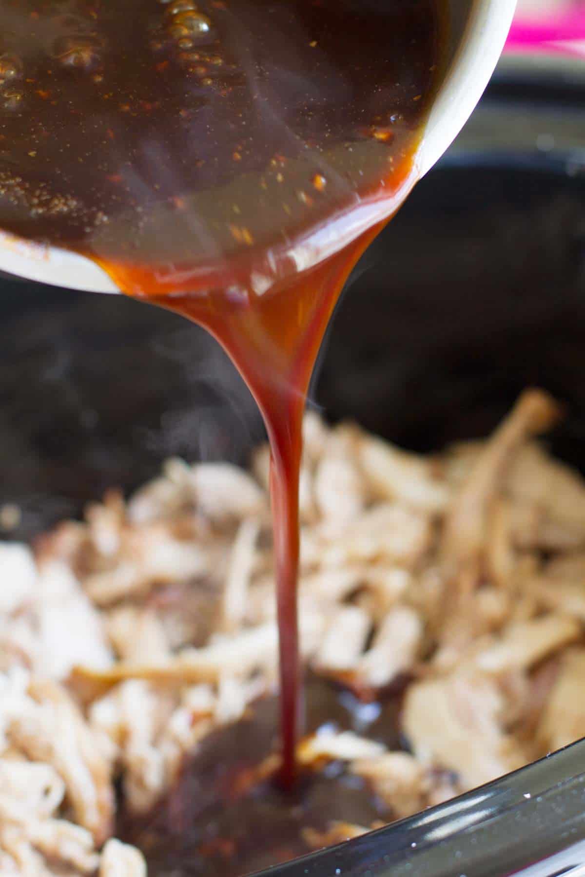 Pouring sauce over slow cooker chicken.