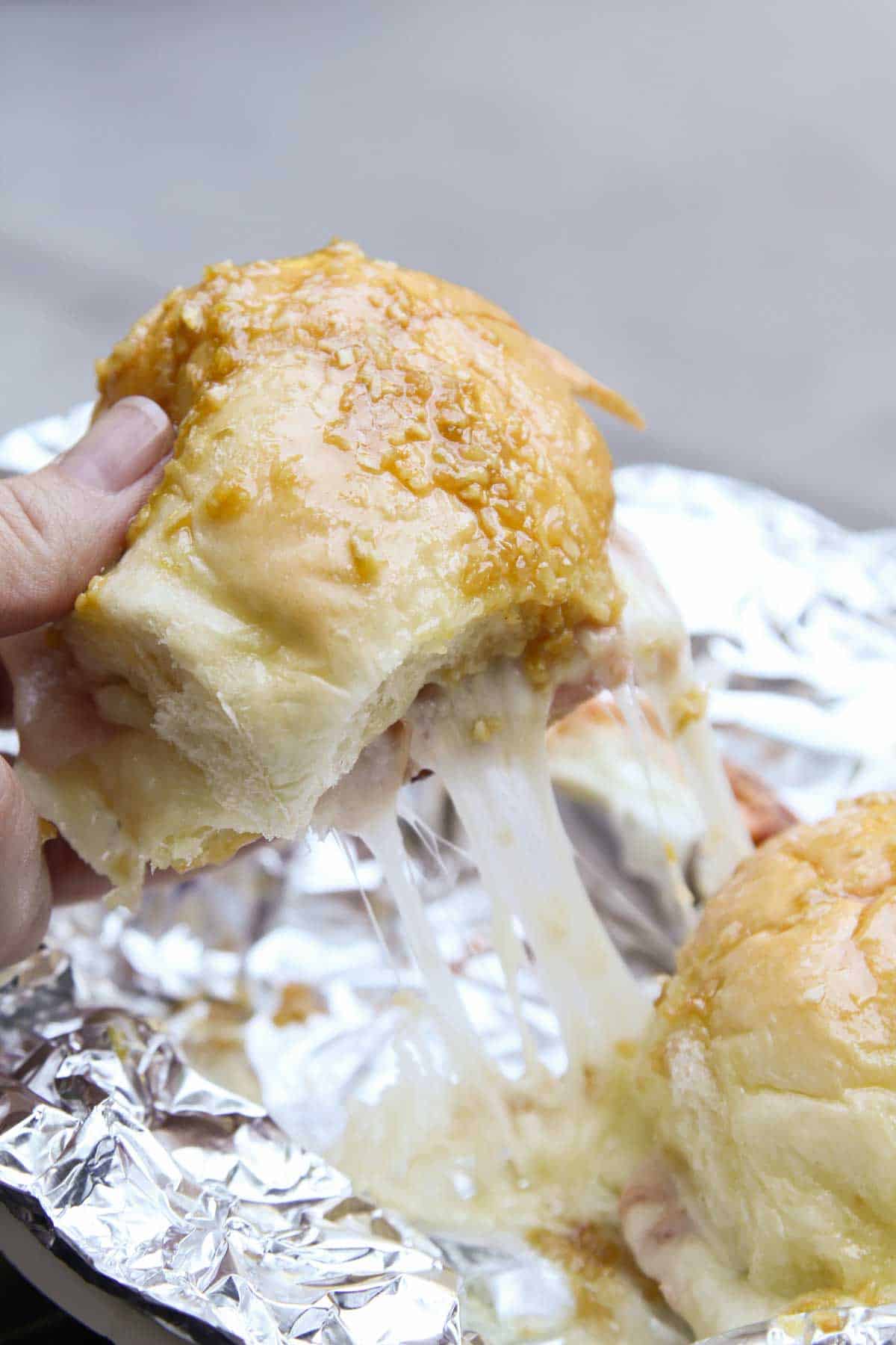 Pulling hot ham and cheese campfire sandwiches apart, showing cheese pull.