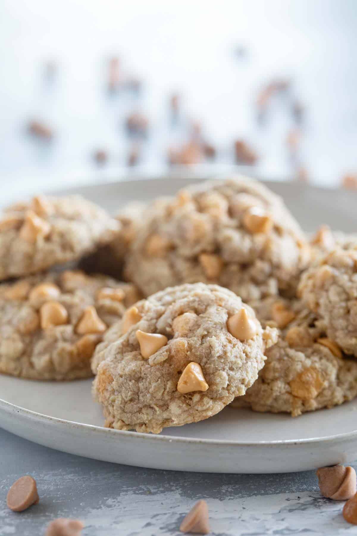 Oatmeal Scotchies on a plate with extra butterscotch chips on the table.