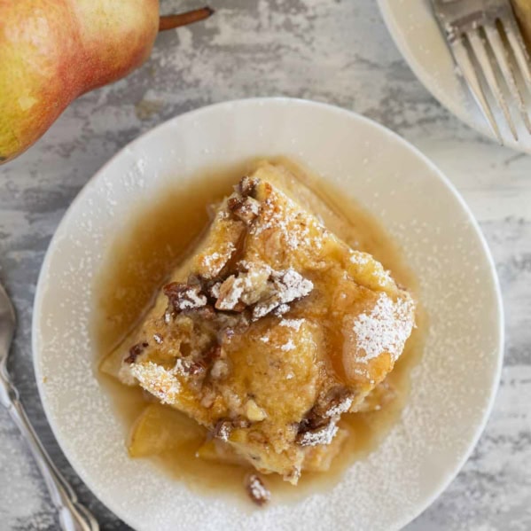 Slice of Pear Baked French Toast on a plate with powdered sugar on top.