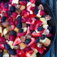 Pound Cake and Berry Campfire Skillet Dessert in a cast iron skillet over a campfire grate.