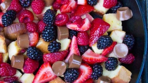 Pound Cake and Berry Campfire Skillet Dessert in a cast iron skillet over a campfire grate.