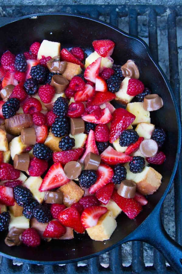 Pound Cake and Berry Campfire Skillet Dessert in a cast iron skillet over a campfire grate.