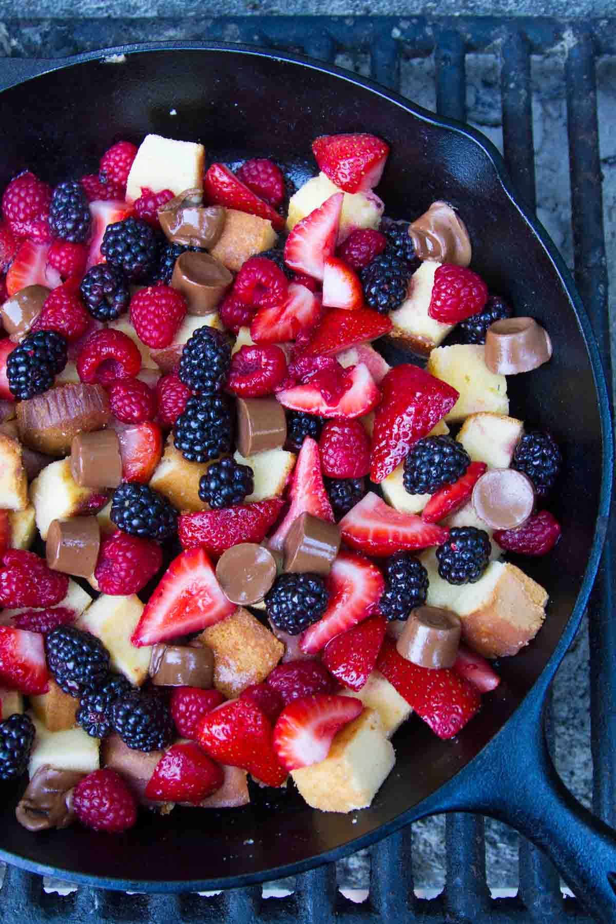 Pound Cake and Berry Campfire Skillet Dessert in a cast iron skillet over a campfire grate.