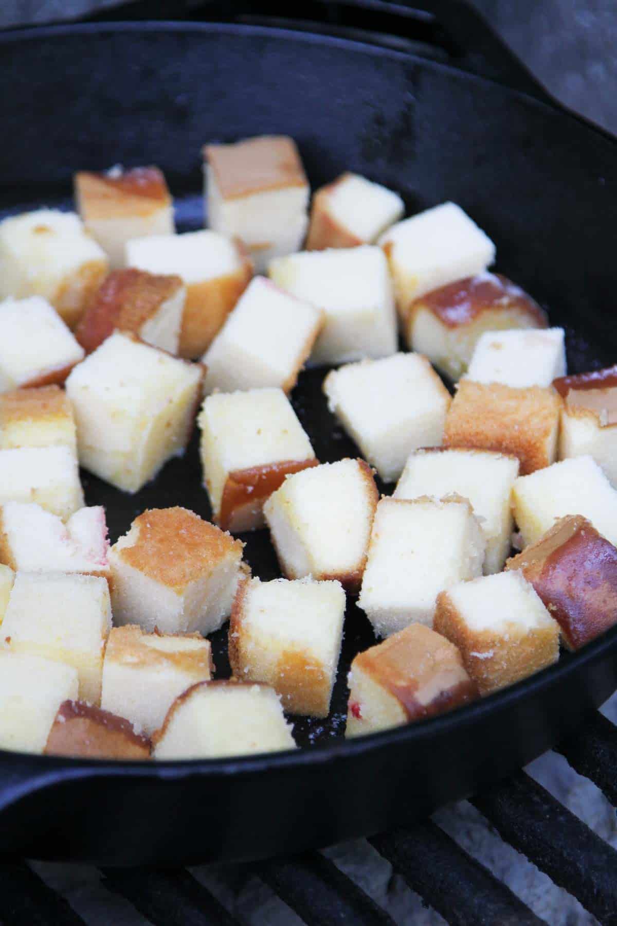 Cubes of pound cake in a cast iron skillet.