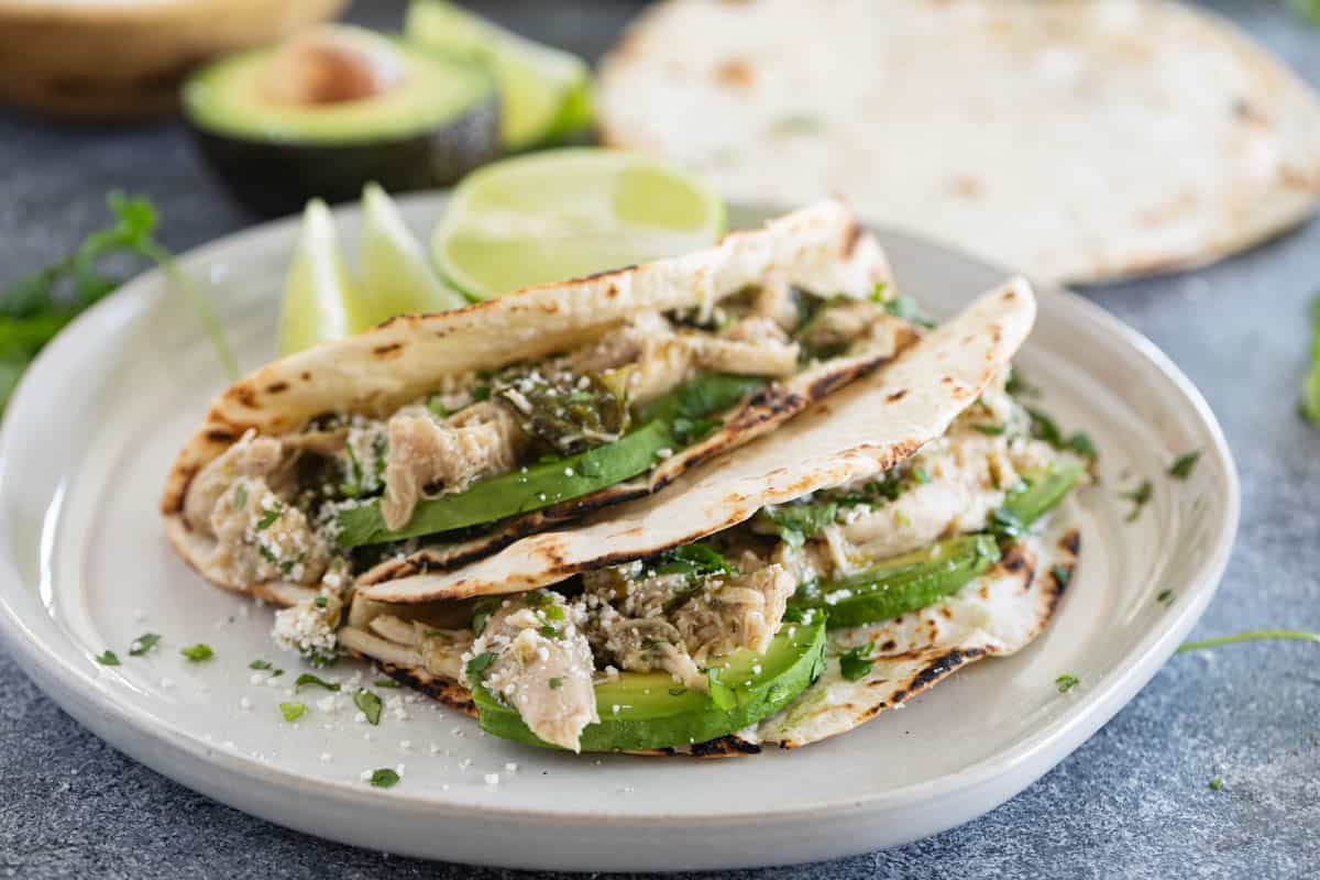 2 Slow Cooker Chicken Tacos on flour tortillas on a plate.