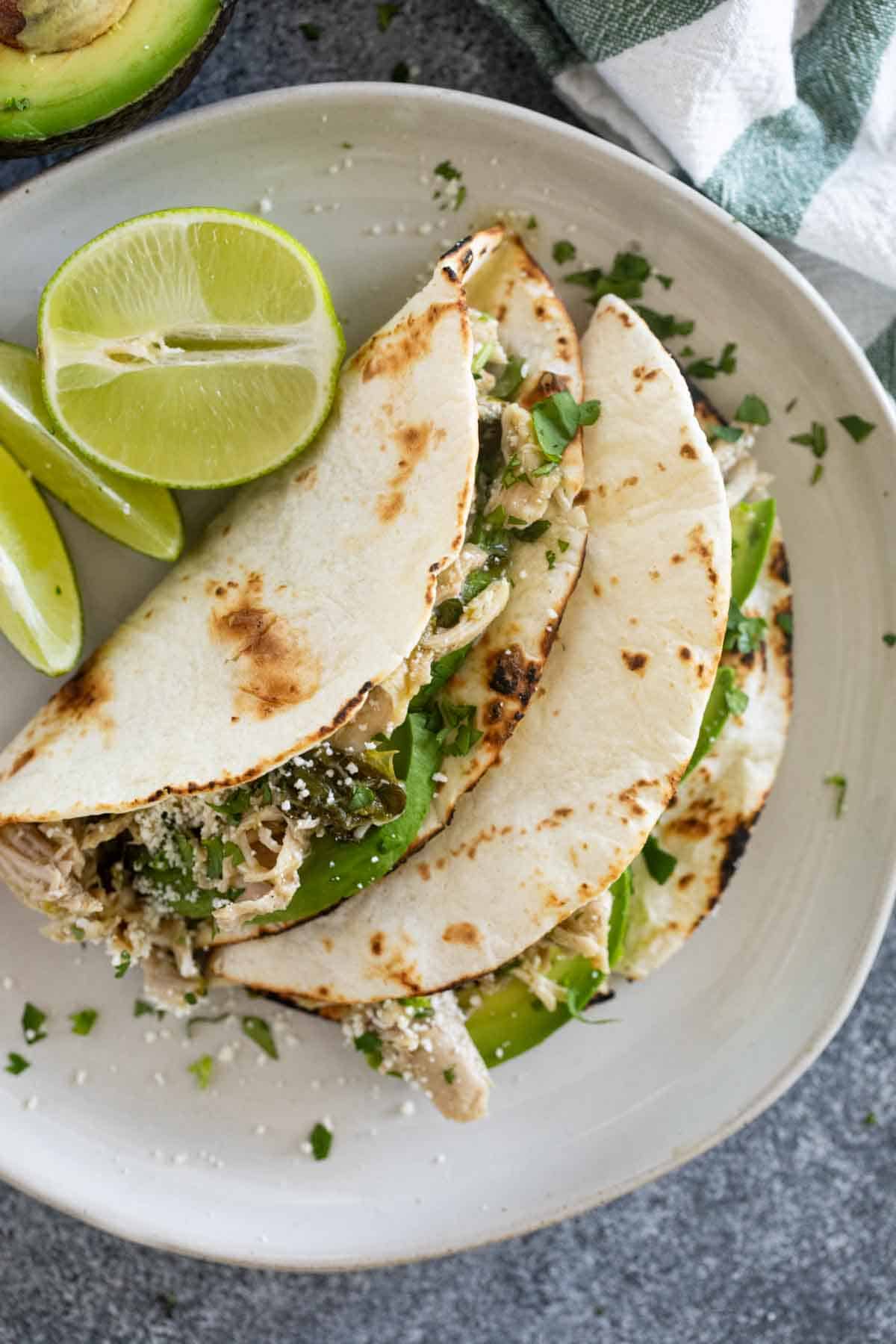 Two slow cooker chicken tacos with charred tortillas.