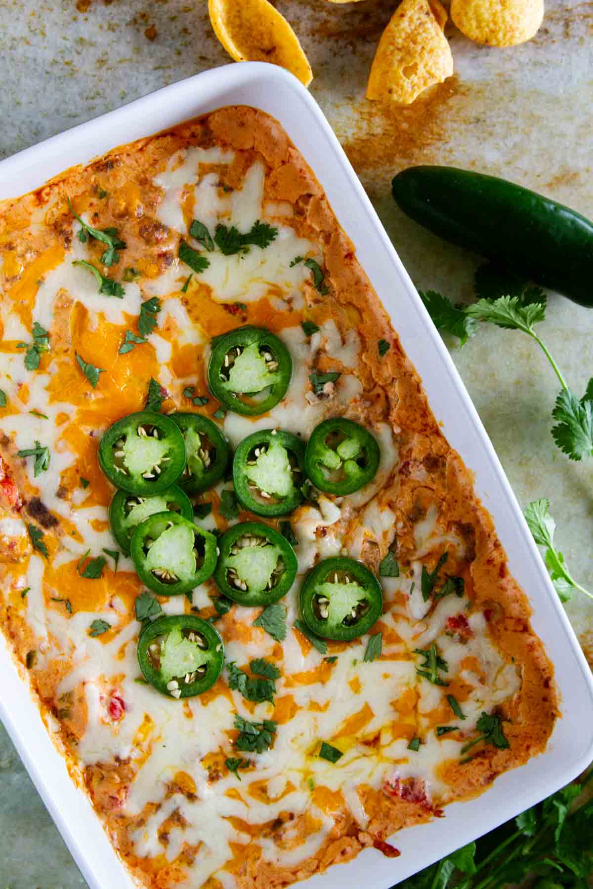 Dish full of spicy sausage dip, topped with fresh jalapeño slices.