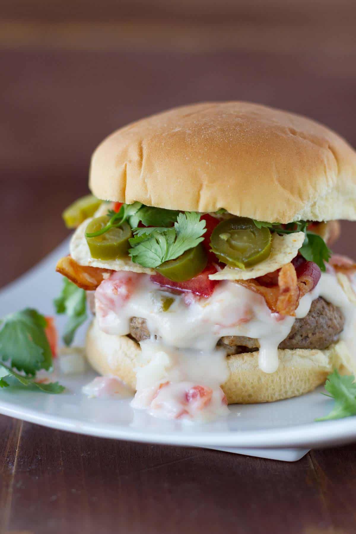 Tex-Mex Bacon Cheeseburgers with queso sauce, jalapeños, and corn chips.