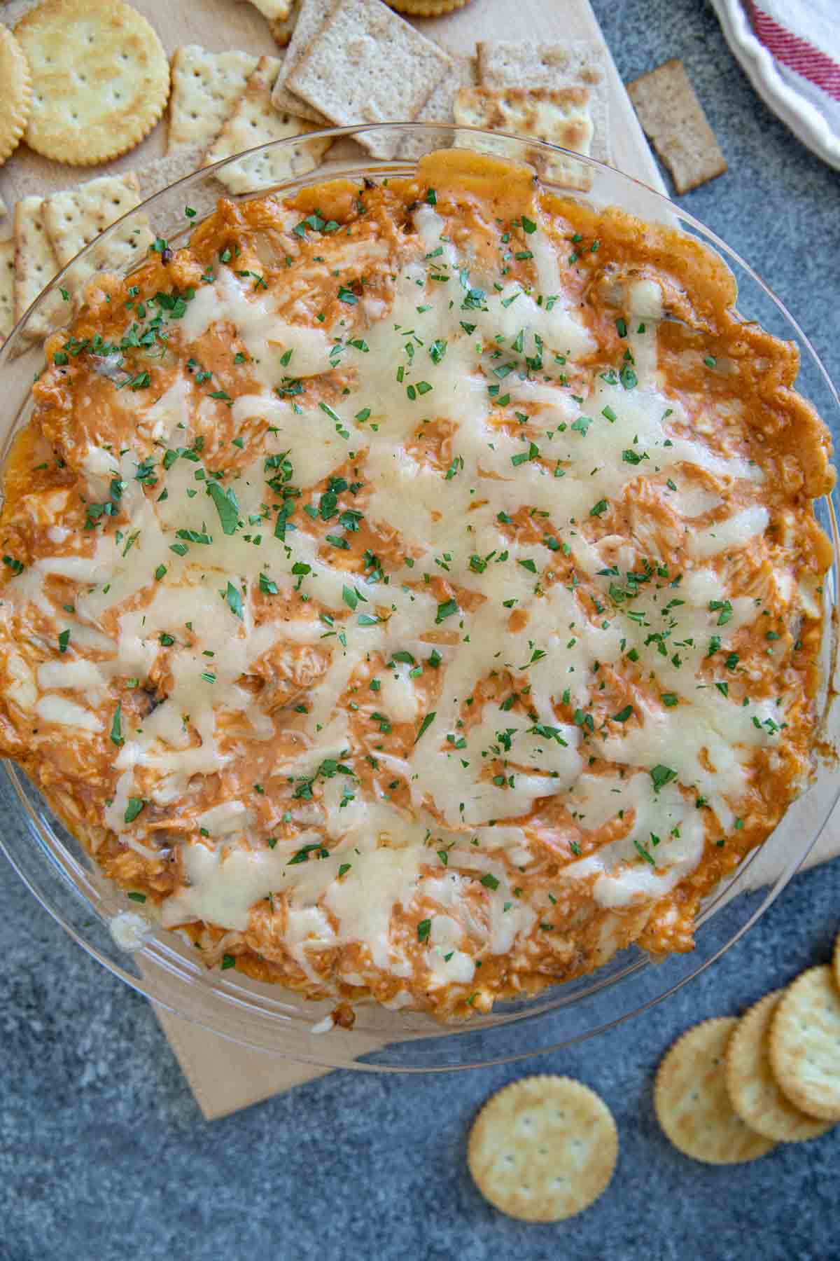 Dish filled with BBQ Chicken Dip surrounded by assorted crackers.