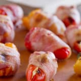 Bacon Wrapped Sausage Stuffed Peppers on a board for serving.