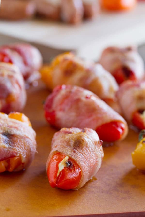 Bacon Wrapped Sausage Stuffed Peppers on a board for serving.