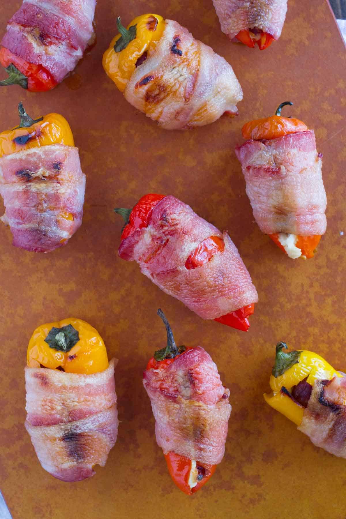 Bacon Wrapped Sausage Stuffed Peppers on a cutting board.