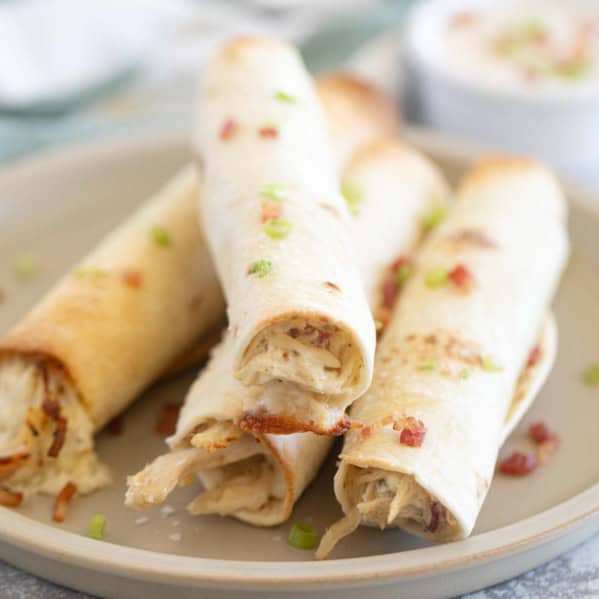 Baked Chicken Bacon Ranch Taquitos stacked on a plate.