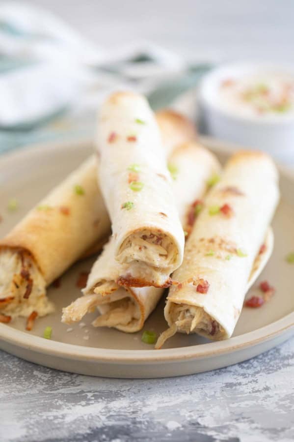 Baked Chicken Bacon Ranch Taquitos stacked on a plate.