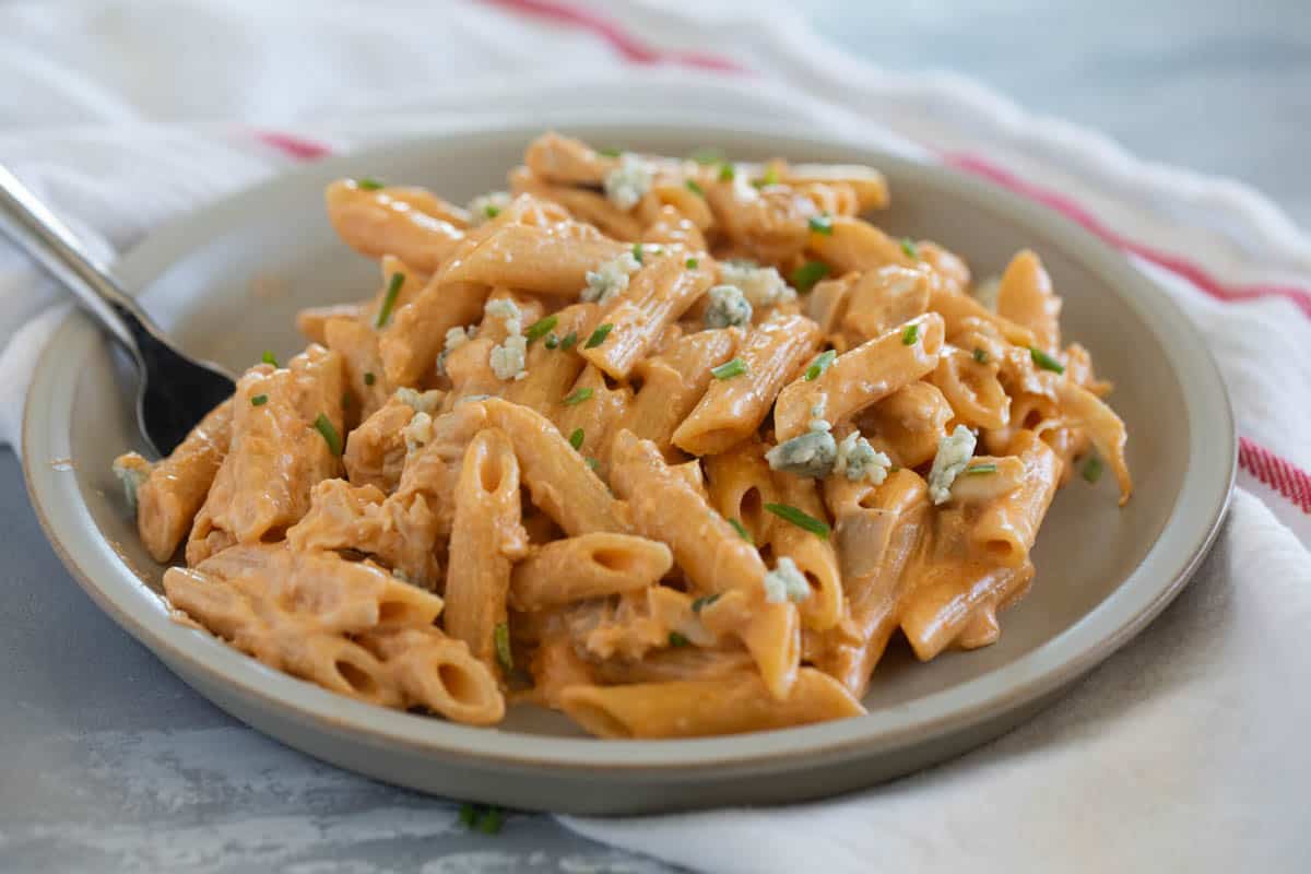 Plate with Buffalo Chicken Pasta, topped with blue cheese and chives.