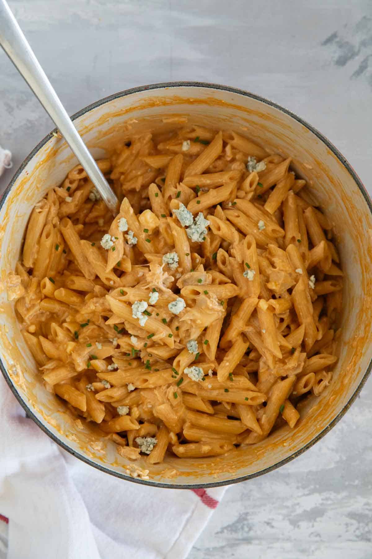 Pot filled with buffalo chicken pasta topped with blue cheese and chives.