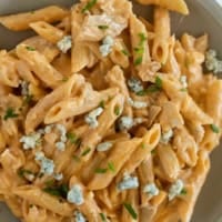 Plate filled with buffalo chicken pasta topped with blue cheese.