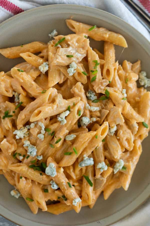 Plate filled with buffalo chicken pasta topped with blue cheese.