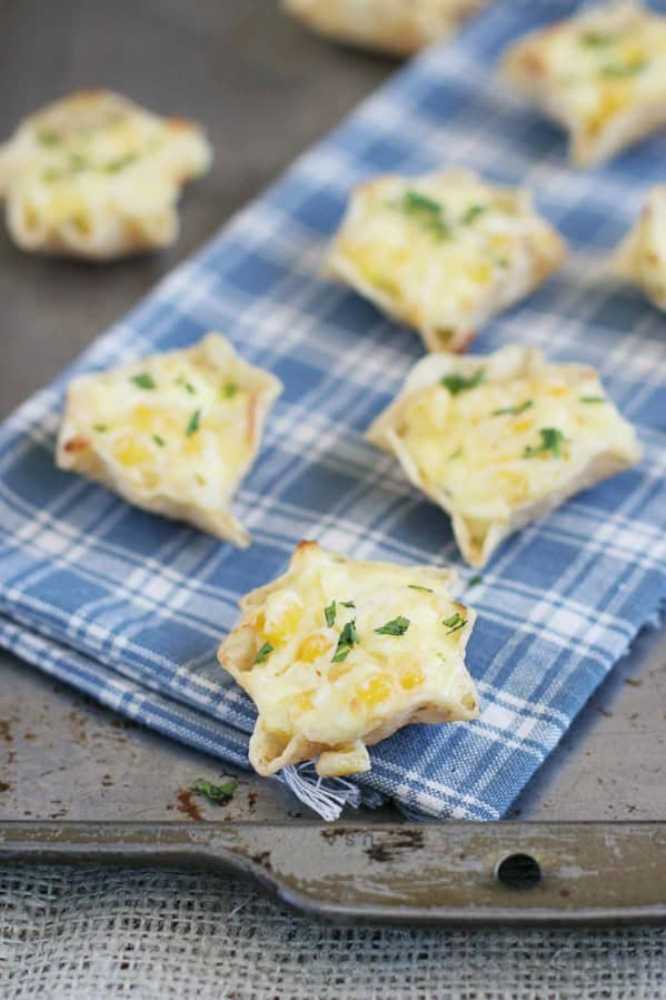 Cheesy Corn Bites topped with cilantro, on a towel over a baking sheet.