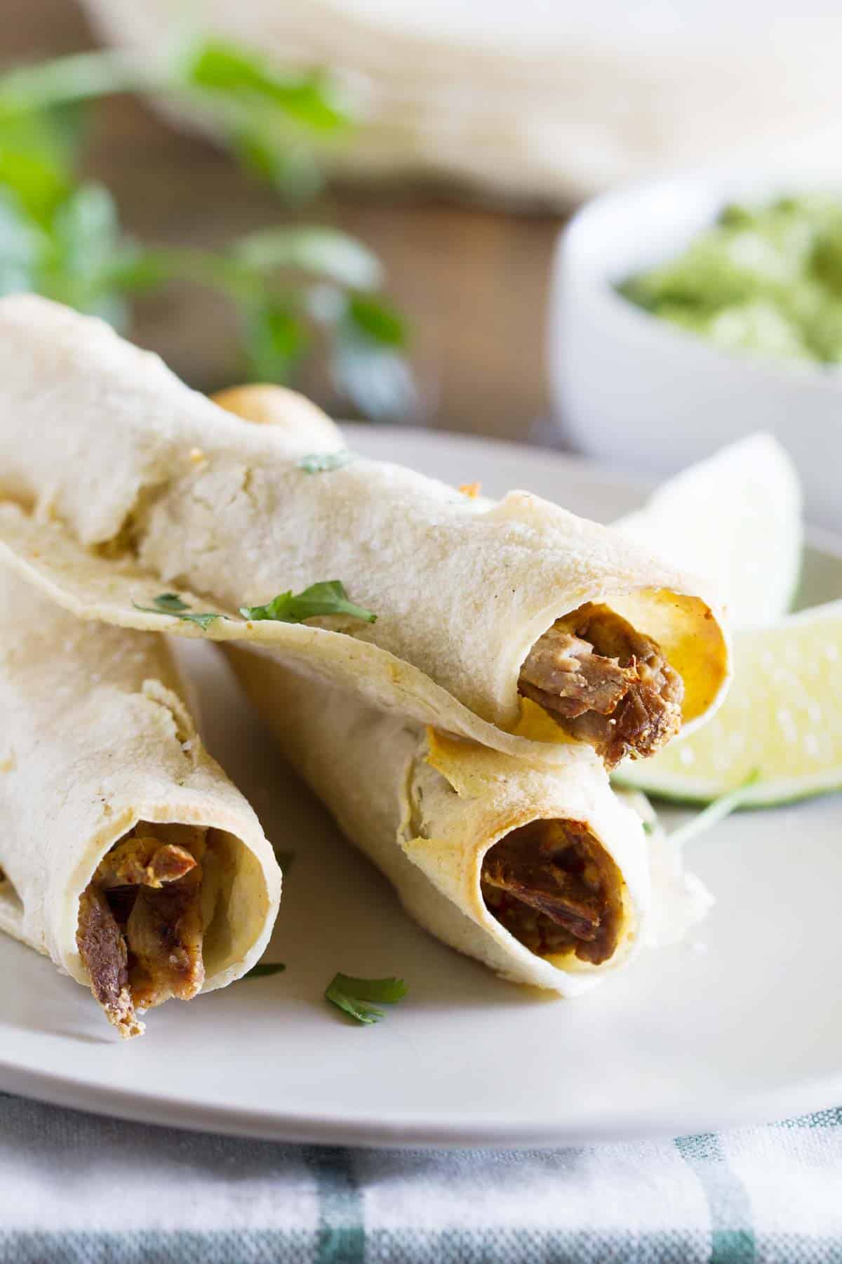 Chipotle Beef Baked Taquitos stacked on a plate.