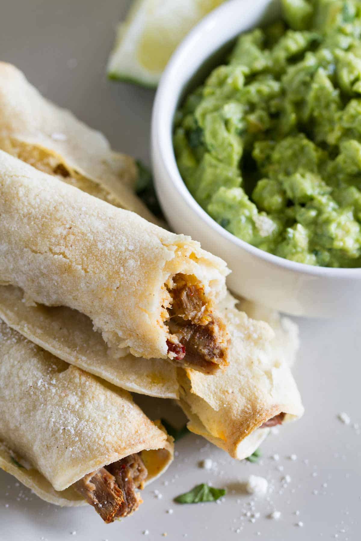 Chipotle Beef Baked Taquitos next to a bowl of guacamole.