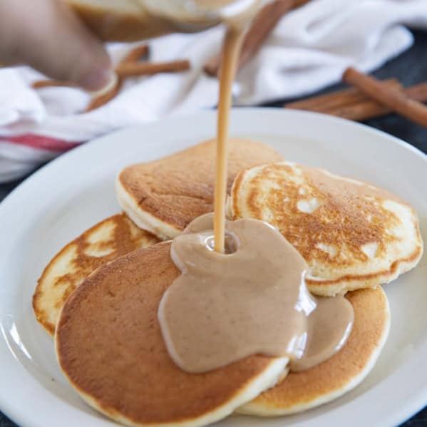 Pouring cinnamon syrup onto pancakes.