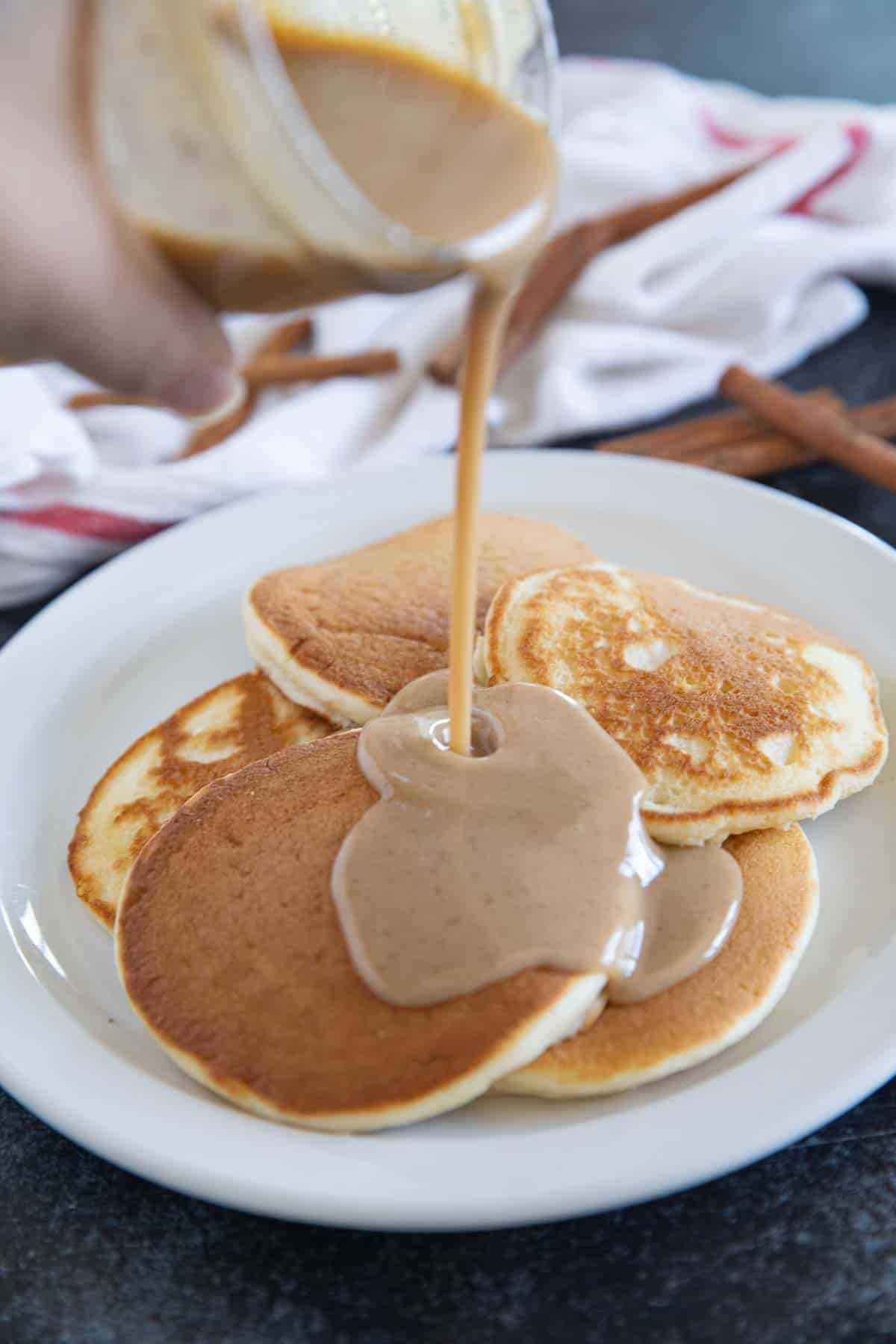 Pouring cinnamon syrup onto pancakes.