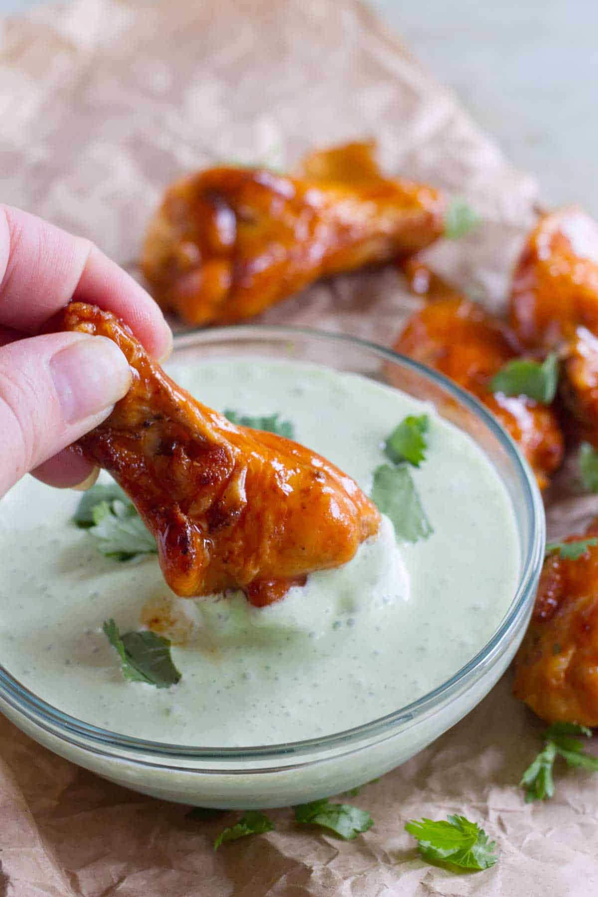 Dipping an enchilada chicken wing into creamy cilantro dip.