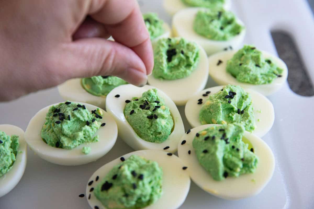 Deviled eggs with green filling and black sesame seeds for Halloween.