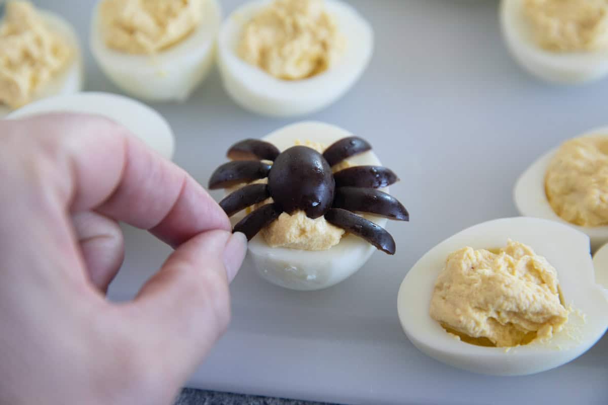 Deviled eggs with a spider on top made from olives.