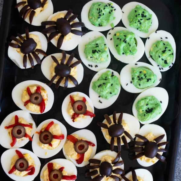 Halloween deviled eggs decorated three ways - green deviled eggs, spider deviled eggs, and deviled eyeballs.