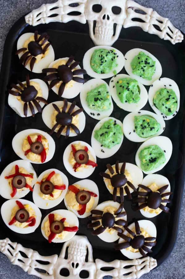 Halloween deviled eggs decorated three ways - green deviled eggs, spider deviled eggs, and deviled eyeballs.