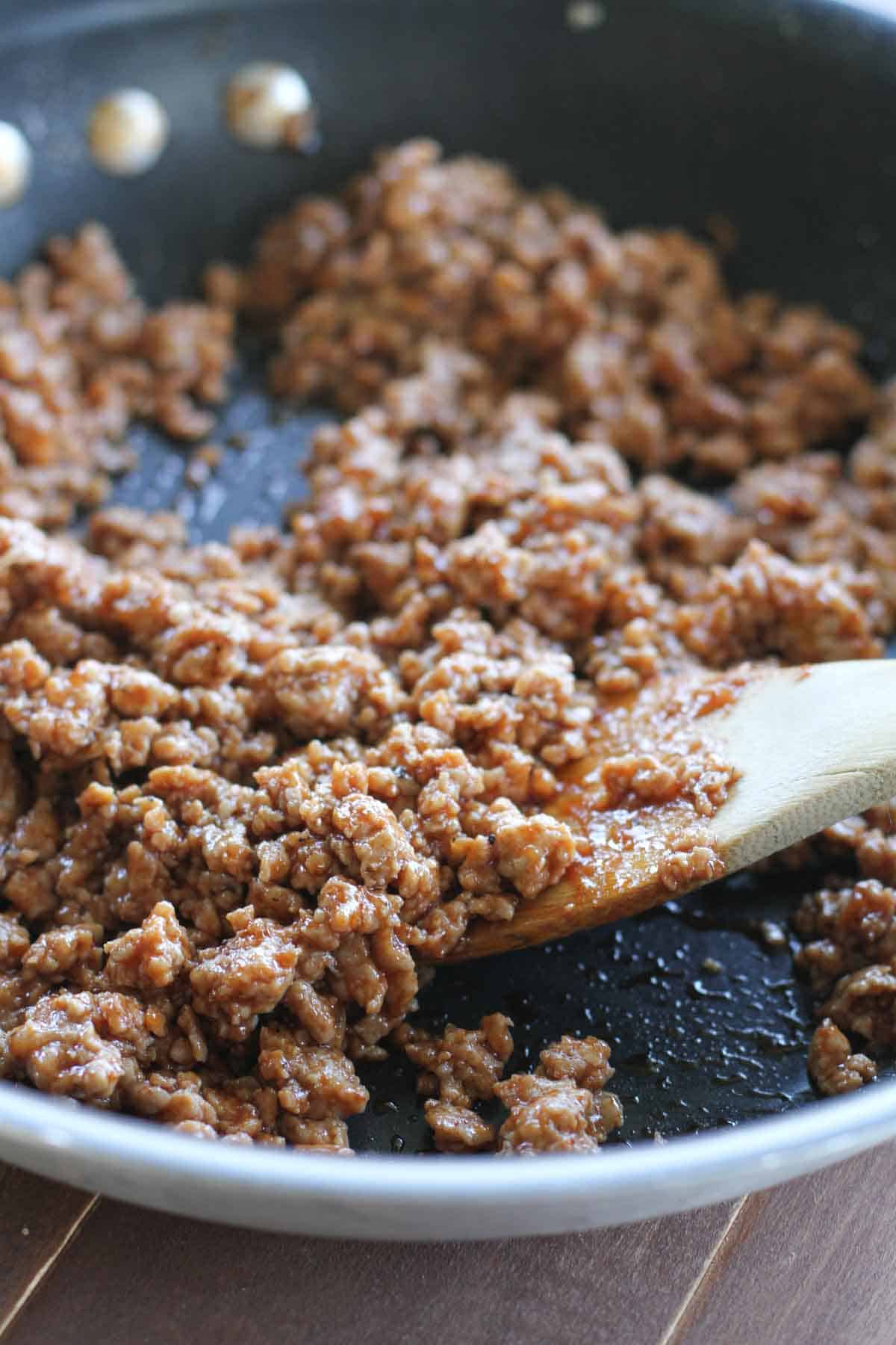 Ground pork with bbq sauce in a skillet.